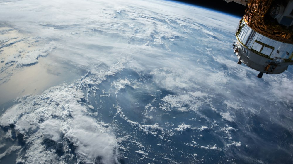 A satellite view of Earth seen from orbit, its cloud cover and oceans spread beneath the spacecraft